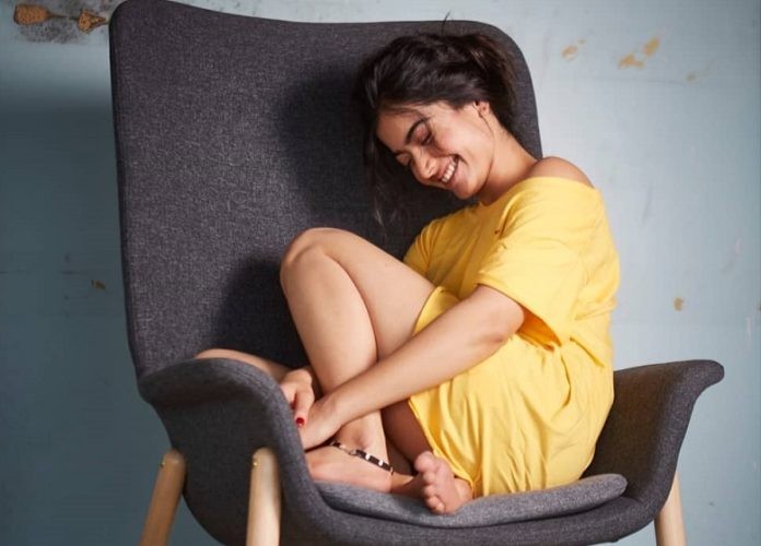 Actress rashmika mandanna hot photos in yellow colour single top seated on chair