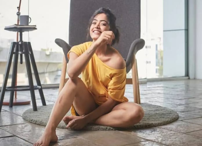 Actress rashmika mandanna hot photos in yellow colour single top seated on chair