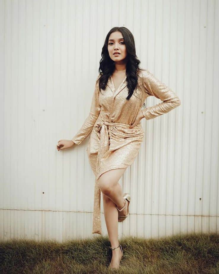 Anikha surendran posing in shining golden glamour dress