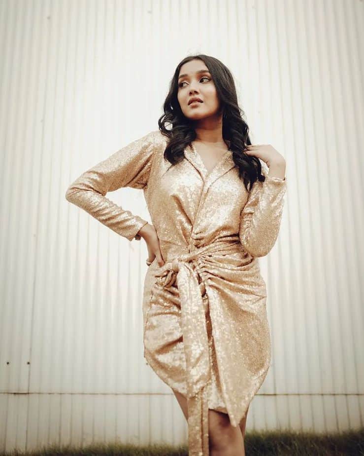 Anikha surendran posing in shining golden glamour dress