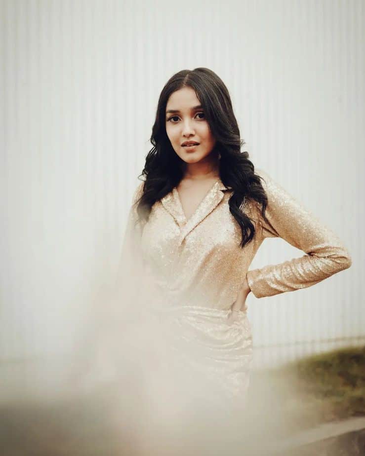 Anikha surendran posing in shining golden glamour dress