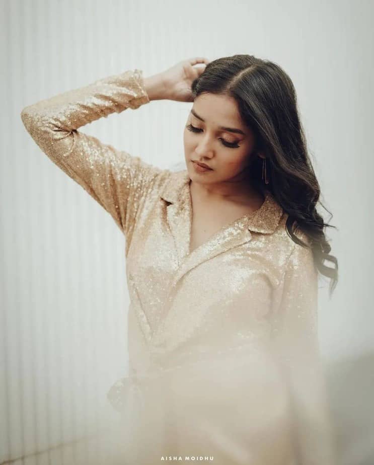 Anikha surendran posing in shining golden glamour dress